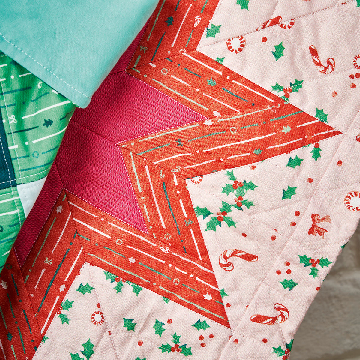 Close-up of a quilt with geometric pattern and Christmas-themed fabric