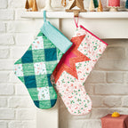Two colorful quilted stockings hanging on a fireplace mantle.