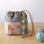 Patchwork drawstring bag with geometric patterns on a wooden surface