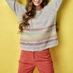 Woman wearing a colorful striped sweater against a yellow background