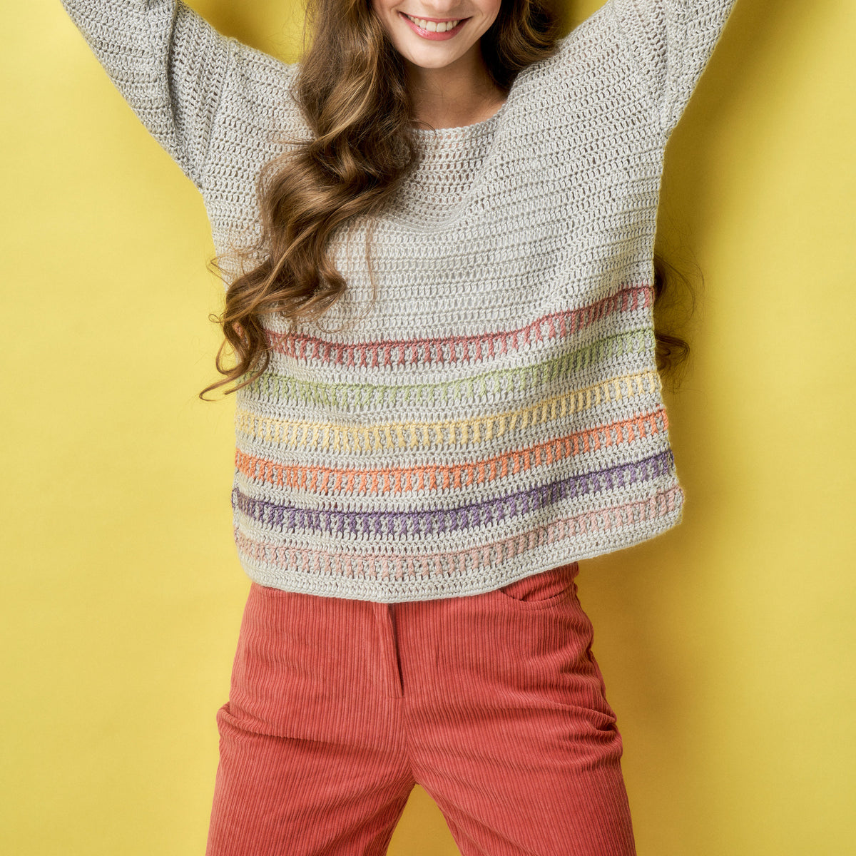 Woman wearing a colorful striped sweater against a yellow background