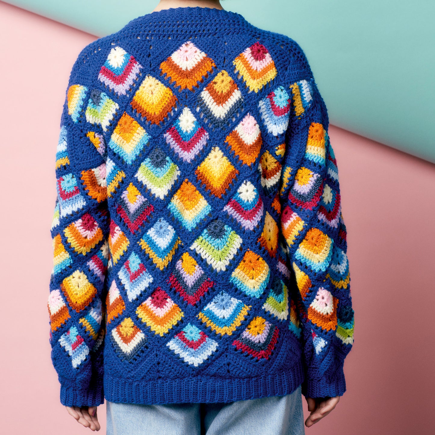 Colorful crocheted sweater with geometric pattern on a plain background