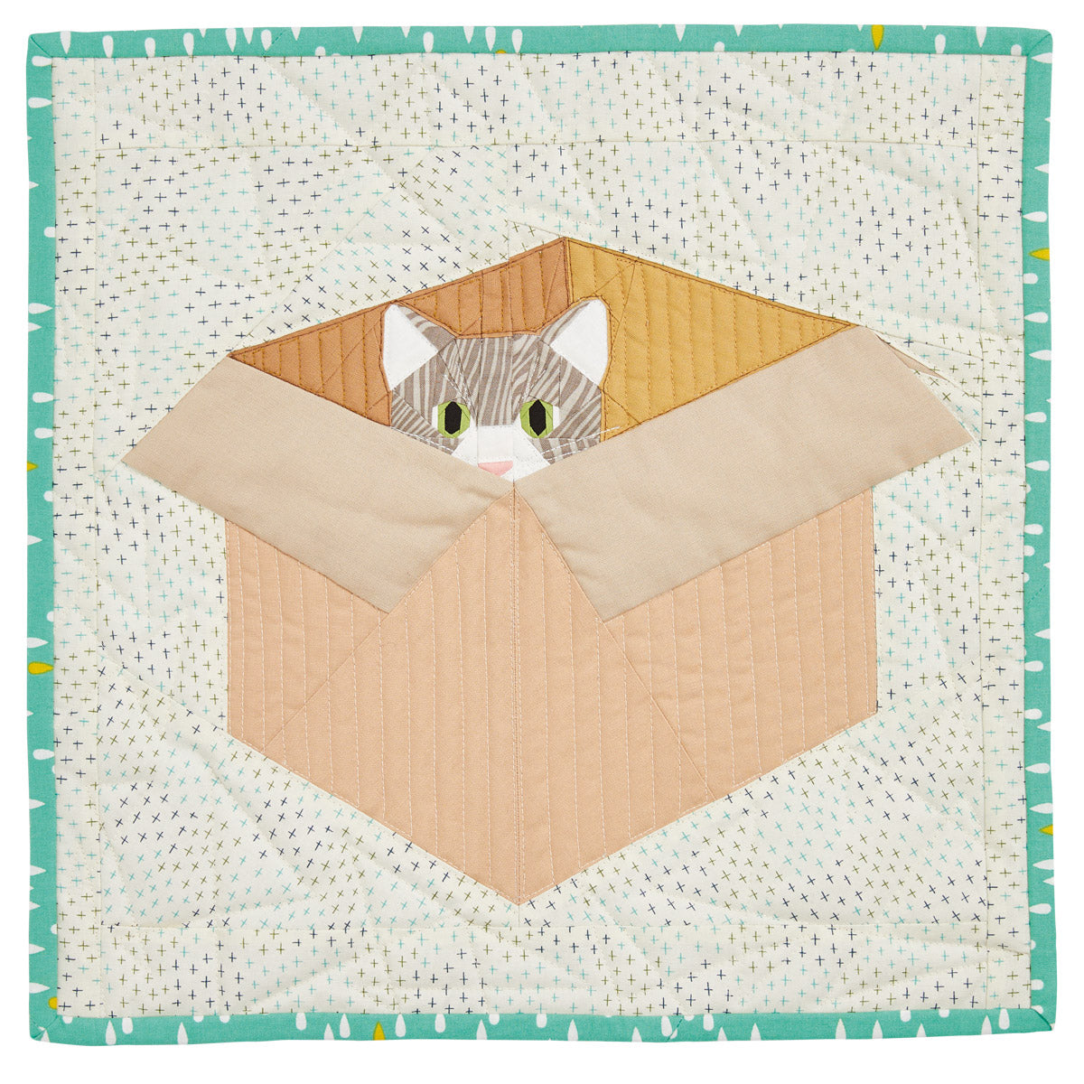 Quilt block with a cat peeking out from a cardboard box on a woven background