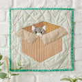 Quilted wall hanging with a cat design on a white background