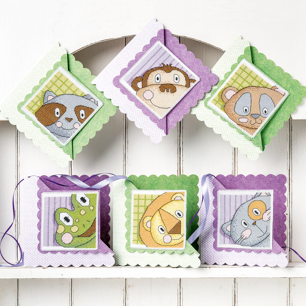 Set of animal-themed cross-stitch patterns on a wooden surface
