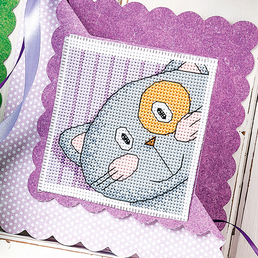 Cross-stitch pattern of an owl on a purple fabric background