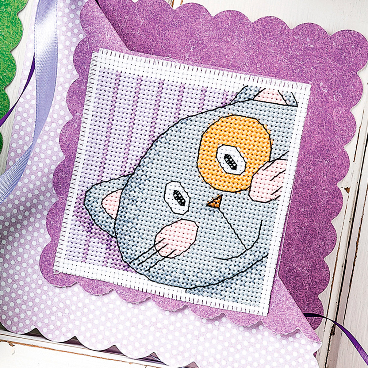 Cross-stitch pattern of an owl on a purple fabric background