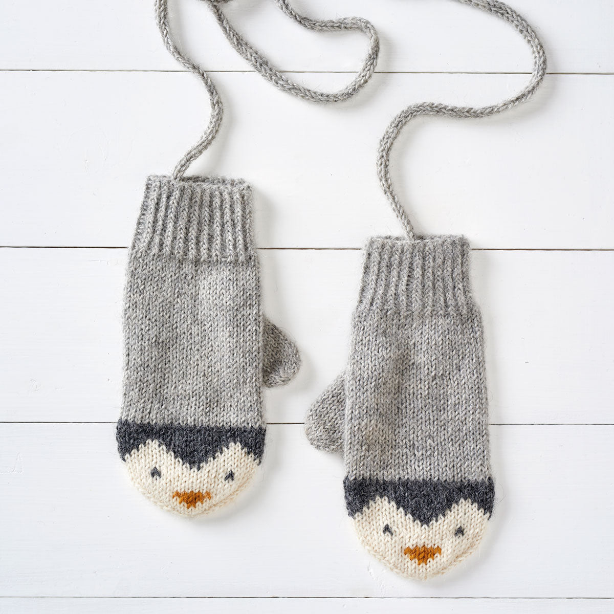 a pair of knitting mittens with a penguin design