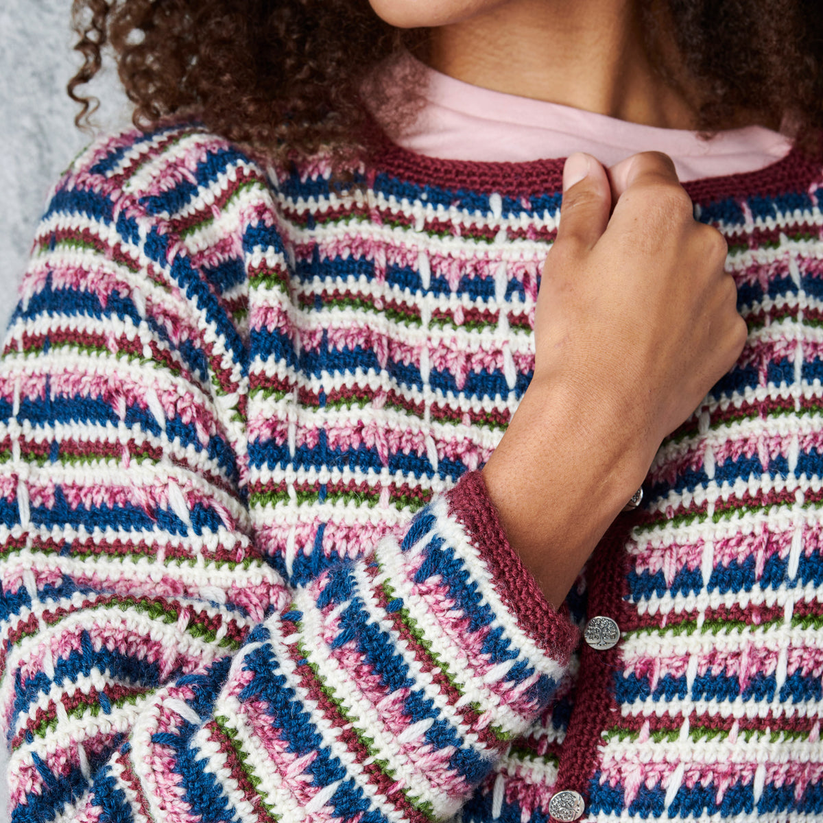 Close-up of a colorful crocheted cardigan with a person wearing it.