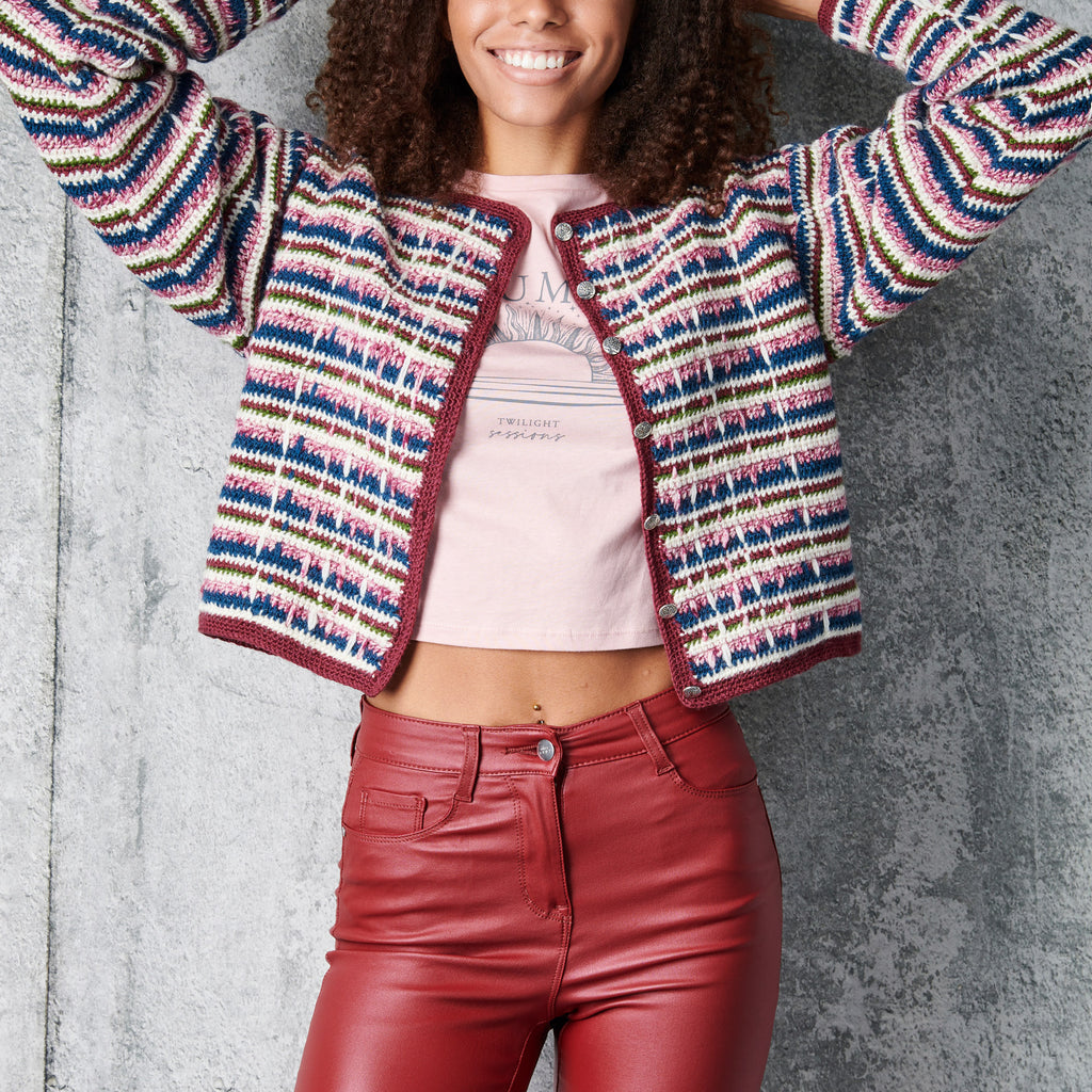 Person wearing a colorful striped cardigan and red pants against a gray background