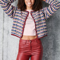 Person wearing a colorful striped cardigan and red pants against a gray background