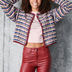 Person wearing a colorful striped cardigan and red pants against a gray background