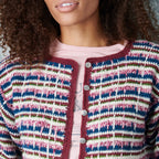 Person wearing a colorful striped crochet cardigan with a neutral background