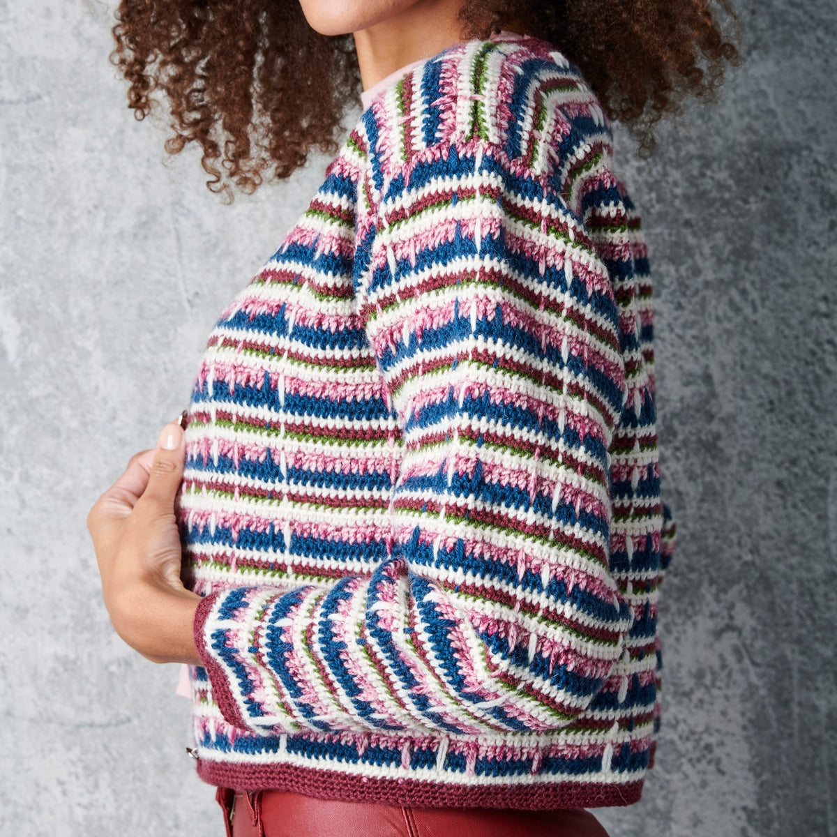 Person wearing a colorful striped sweater against a gray background