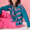 Woman wearing a blue and pink striped sweater against a pink background