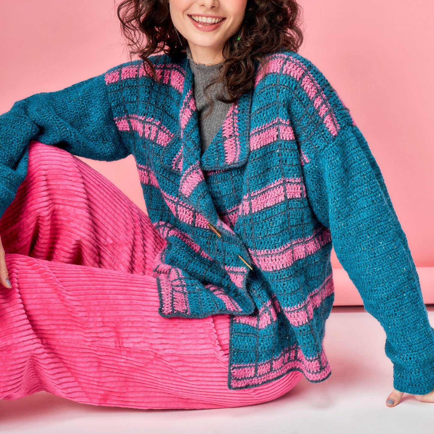 Woman wearing a blue and pink striped sweater against a pink background