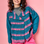 Person wearing a blue and pink striped crochet sweater on a pink background