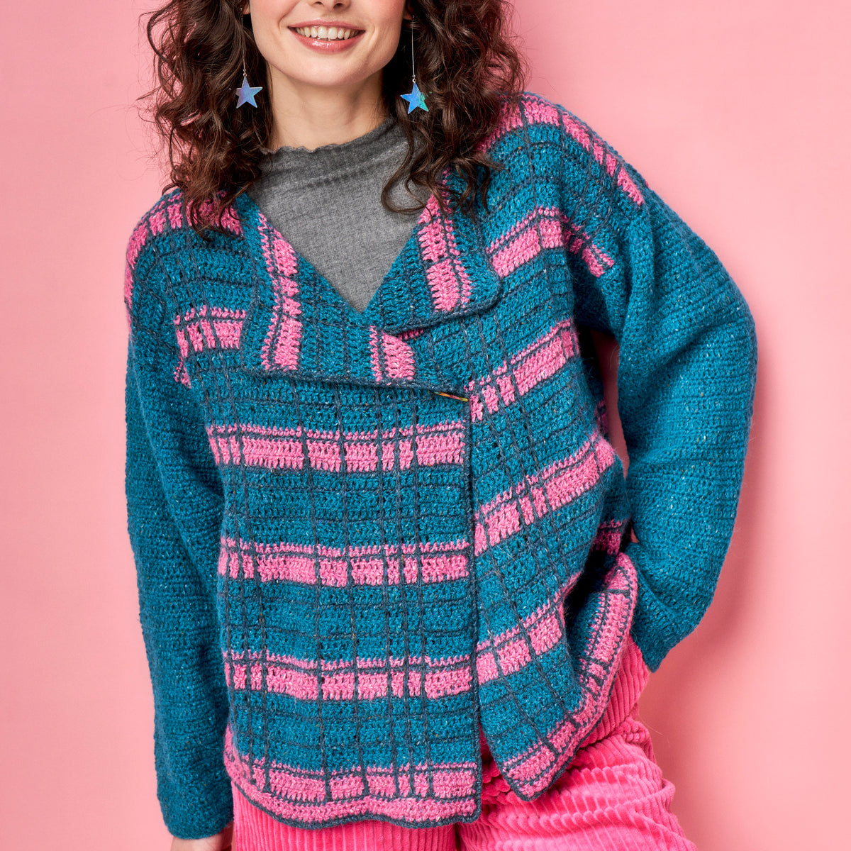 Person wearing a blue and pink striped crochet sweater on a pink background