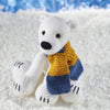 A super cute knitted polar bear wearing a blue and yellow scarf