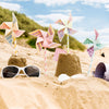 Colorful pinwheels and sunglasses on sand with a scenic background