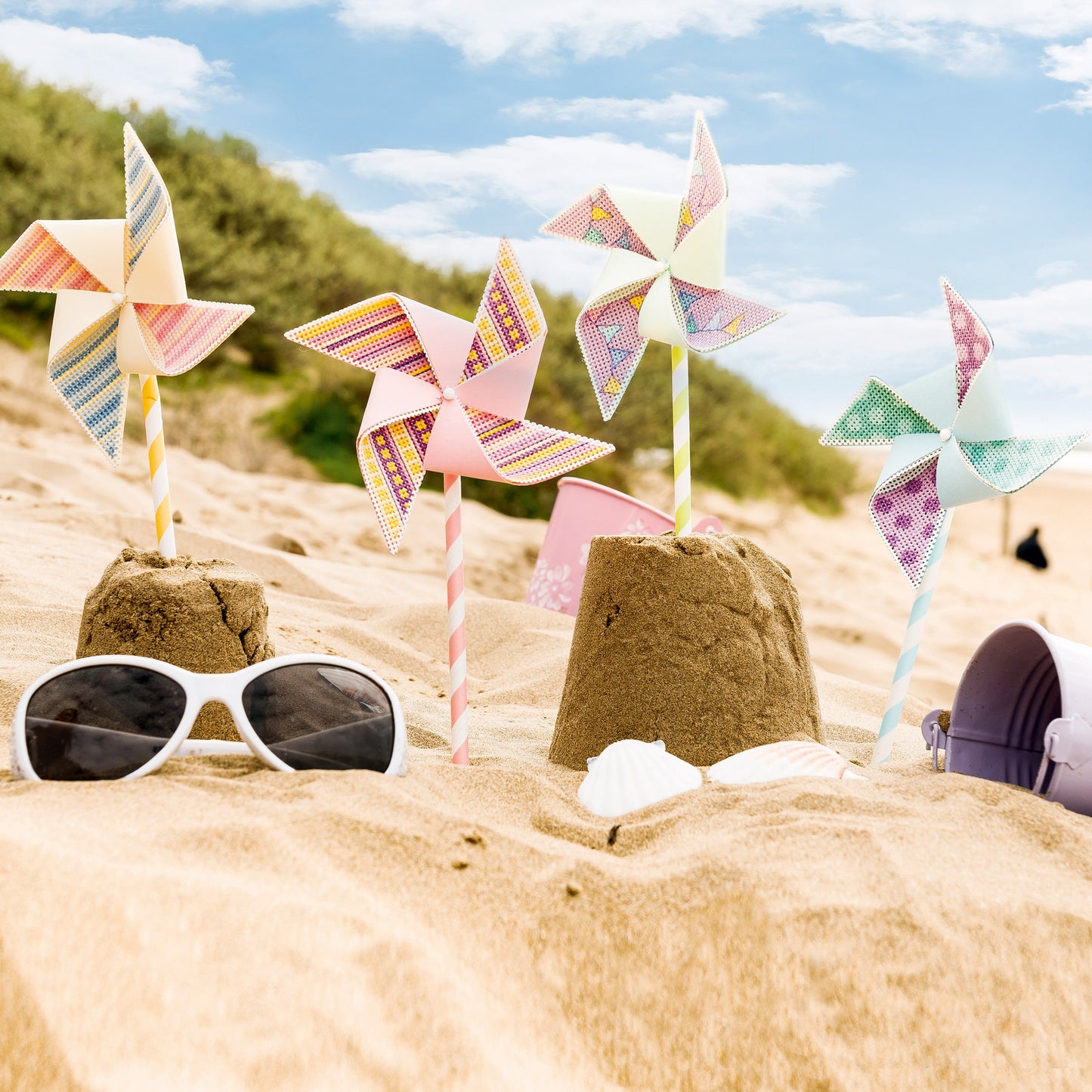 Colorful pinwheels and sunglasses on sand with a scenic background