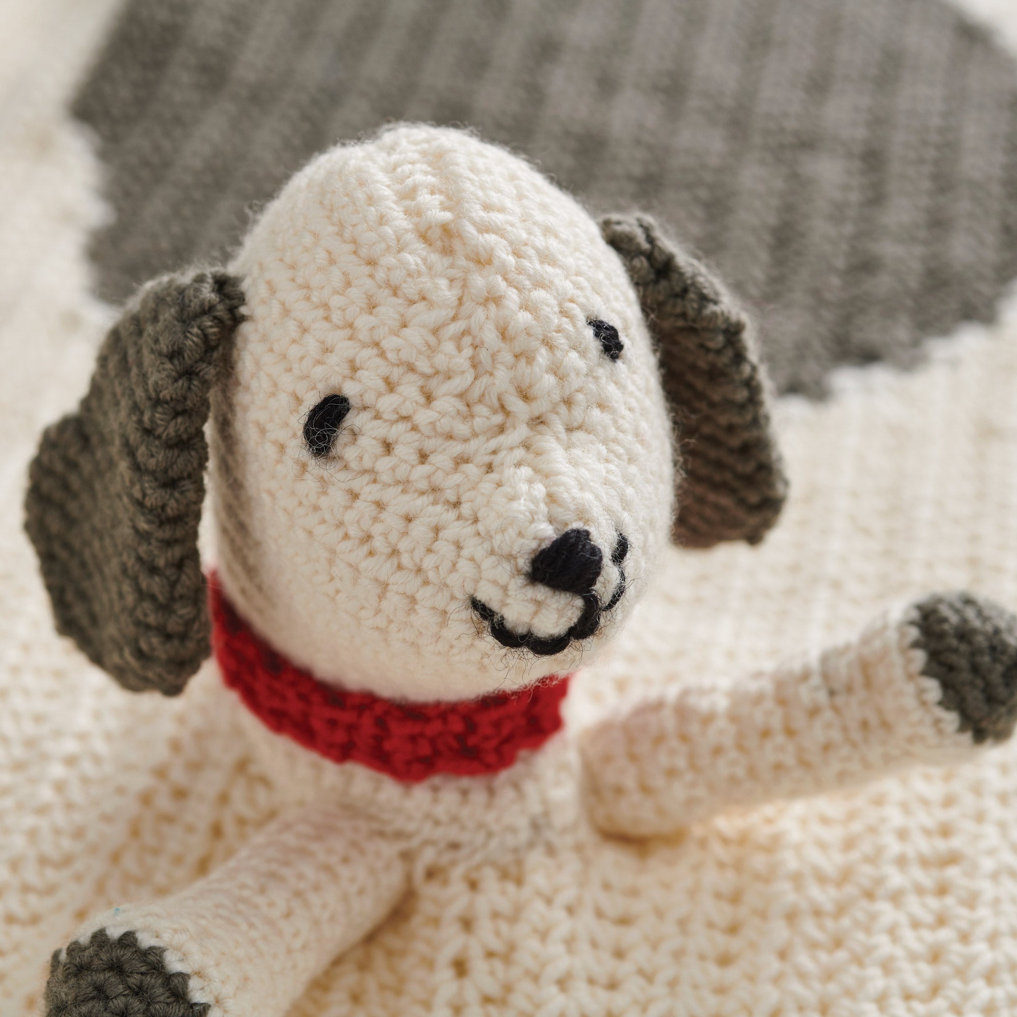 Crochet dog toy with a red collar on a soft surface