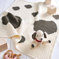 Crochet blanket with dog pattern and toy on a wooden floor