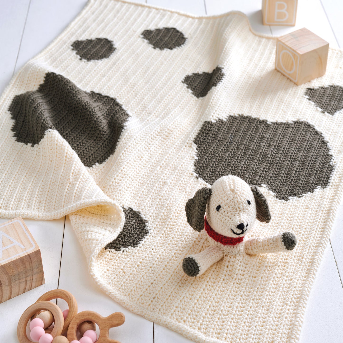 Crochet blanket with dog pattern and toy on a wooden floor