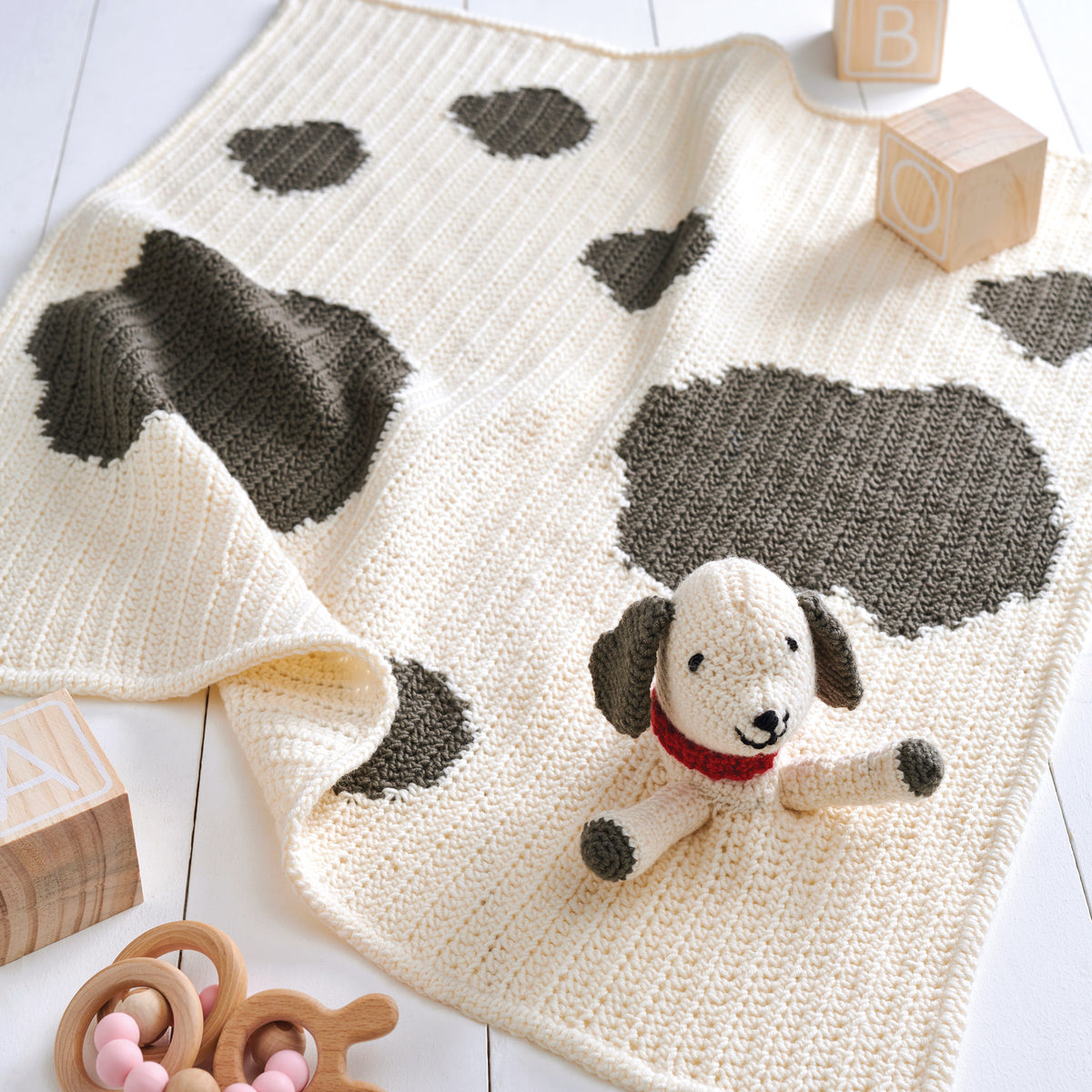 Crochet blanket with dog pattern and toy on a wooden floor