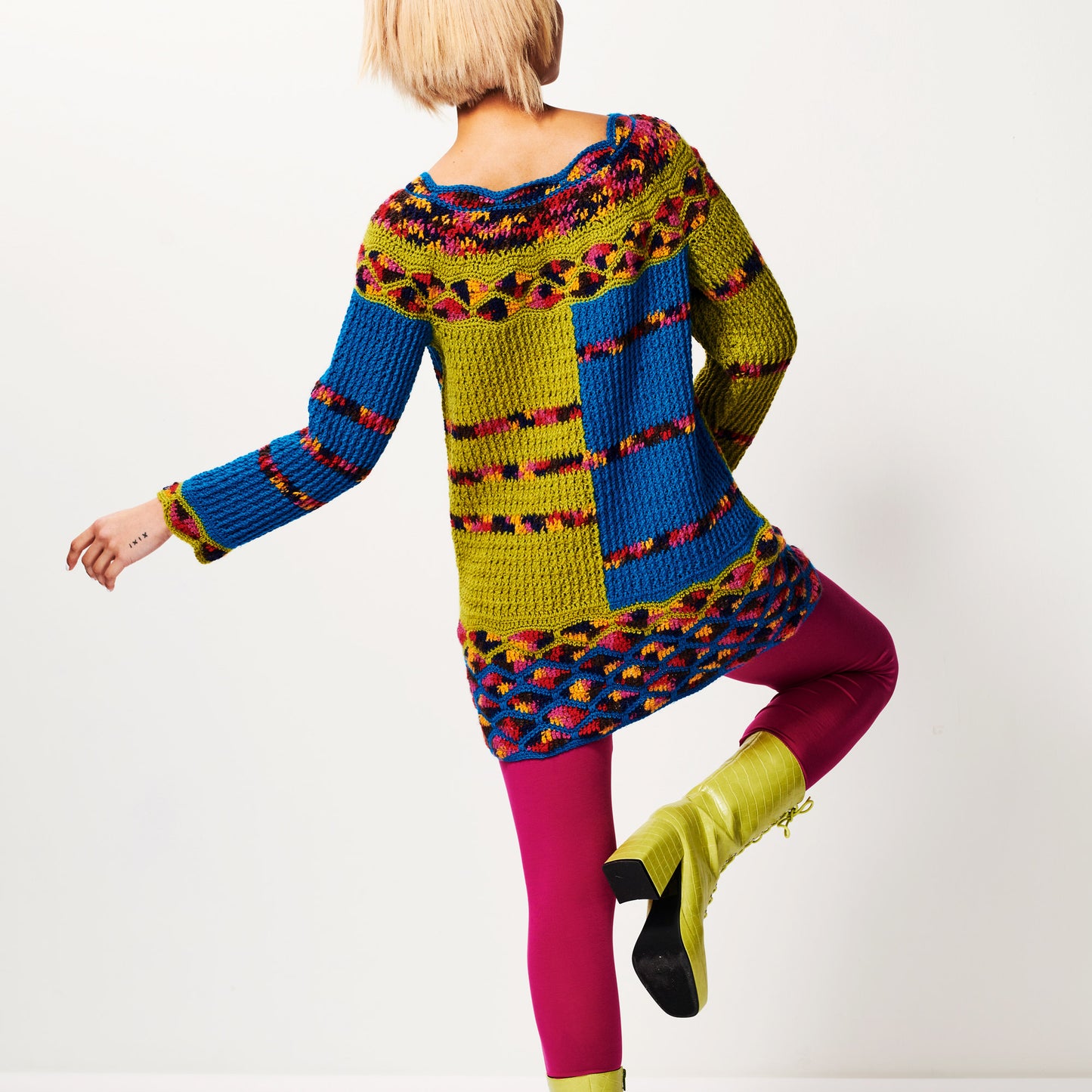 Person wearing a colorful, patterned sweater with a white background