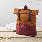 Brown and maroon backpack on a wooden surface with a light gray background