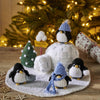 Knitted penguins and an igloo with a Christmas tree in the background