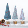 Three decorative knitted Christmas trees on wooden bases with a white background
