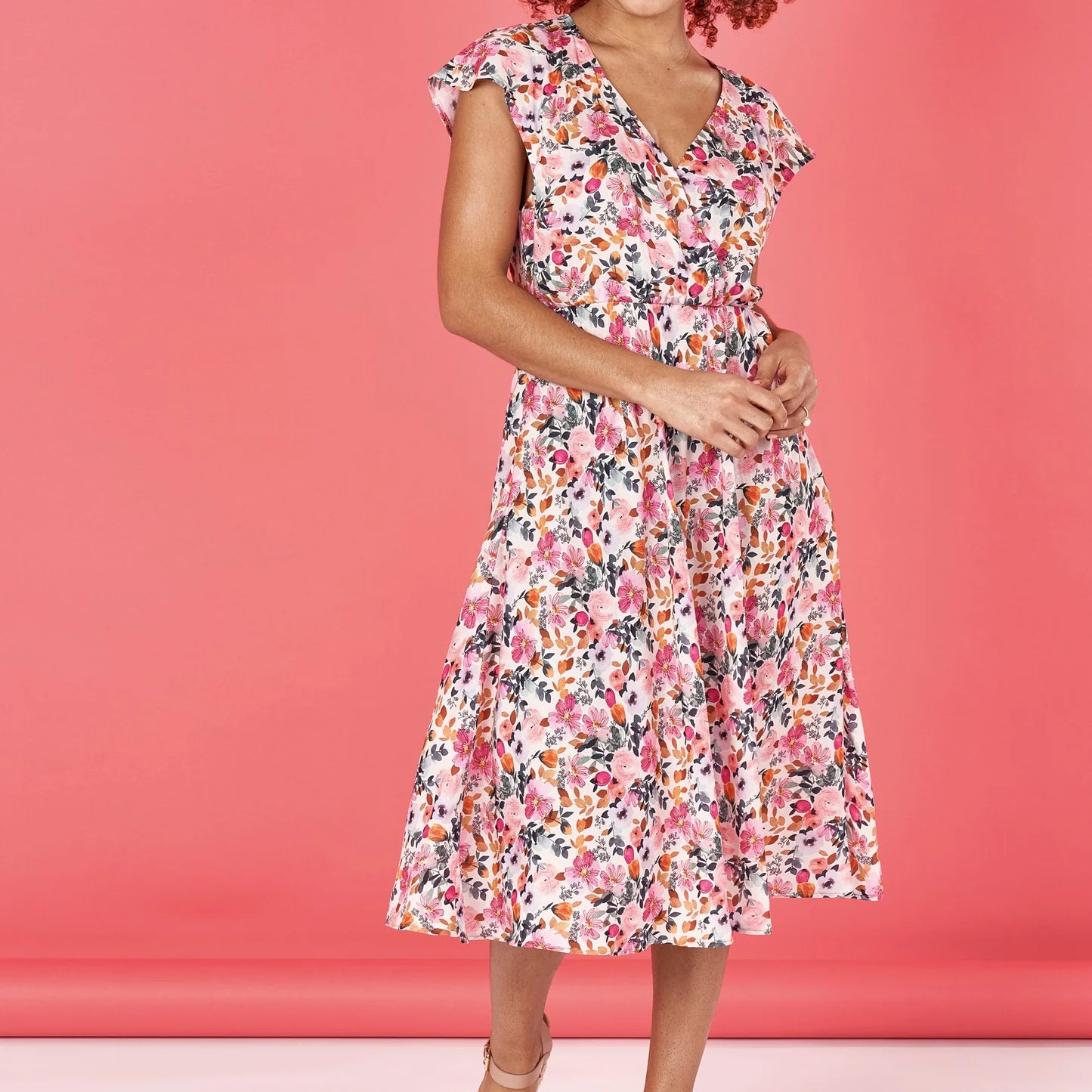 Woman wearing a floral dress against a pink background