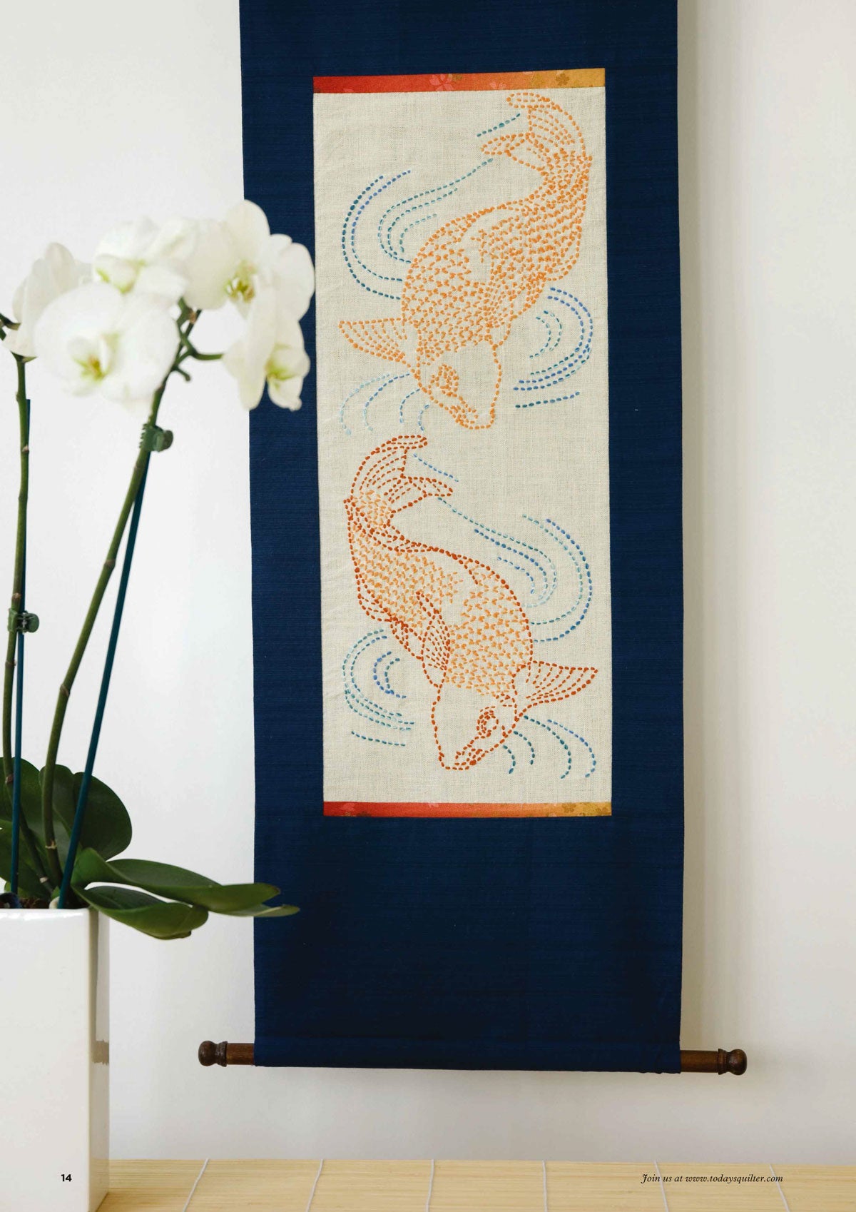 A fabric wall hanging depicts two orange koi fish with swirling blue lines on a cream background. An orchid in a white pot decorates the left side.
