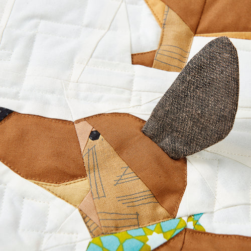 Close-up of a patchwork quilt with a dog face design.