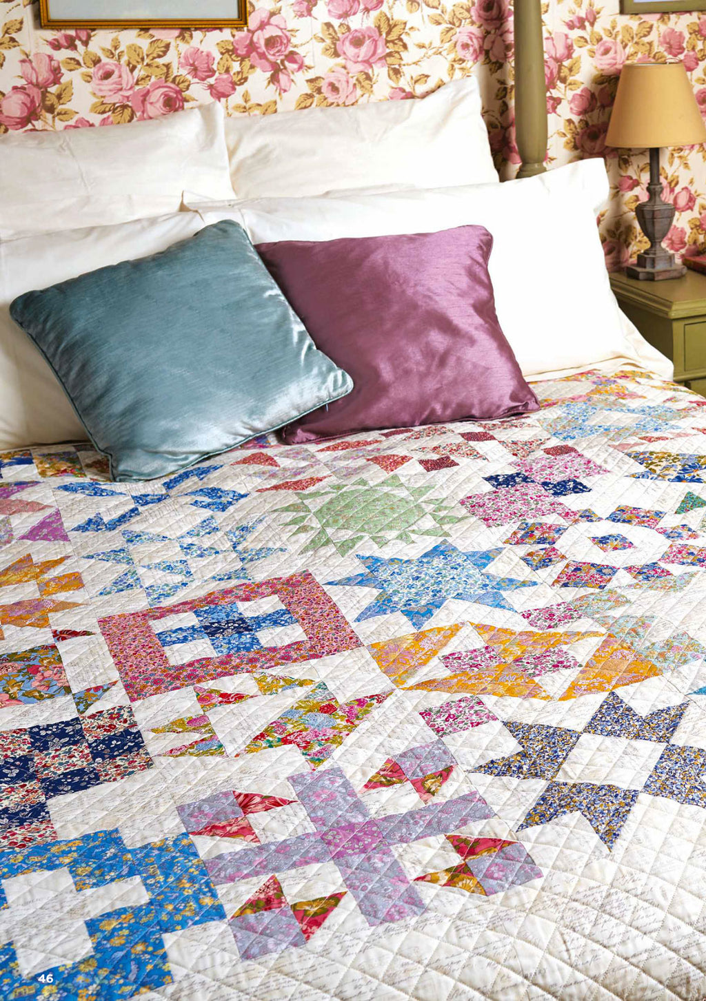 A quilt with various colorful geometric patterns displayed on a bed with decorative pillows.