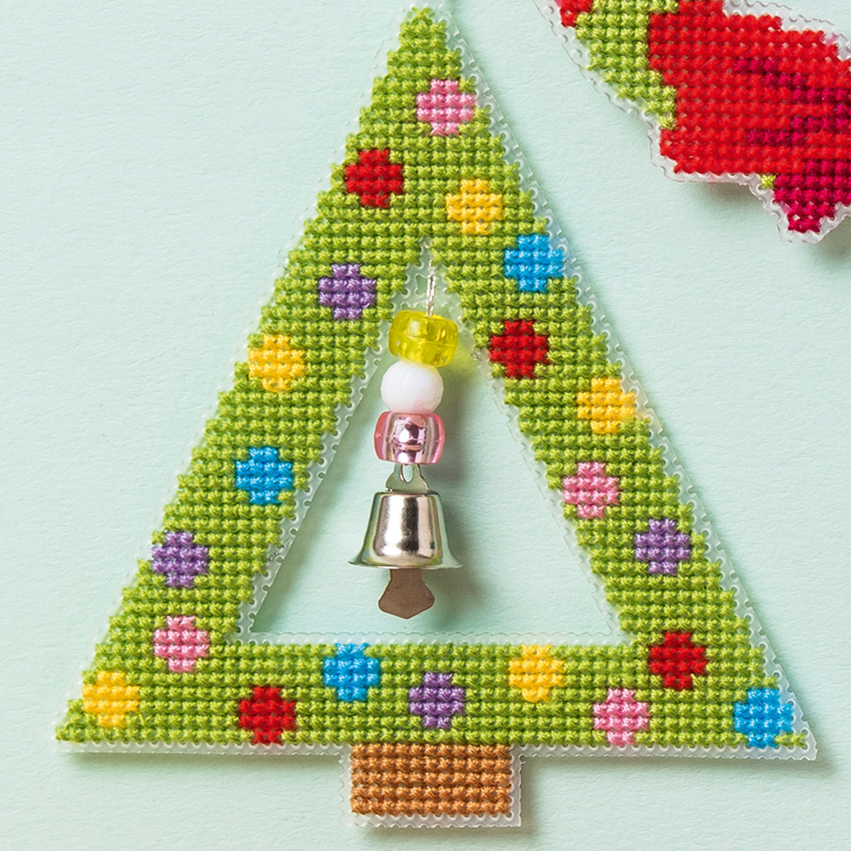 Triangular ornament with colorful pattern and bell on a light blue background