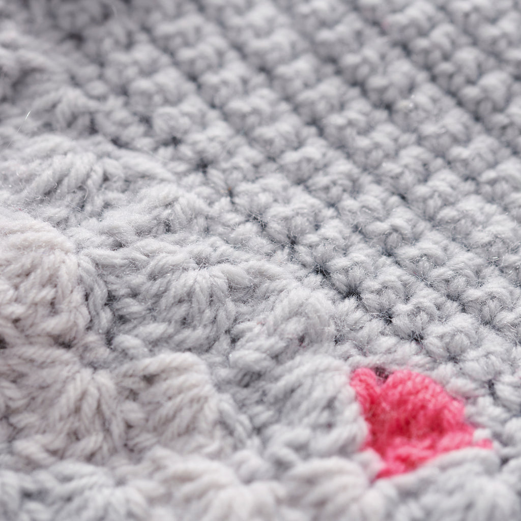 Close-up of textured gray fabric with a pink yarn ball.