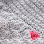 Close-up of textured gray fabric with a pink yarn ball.