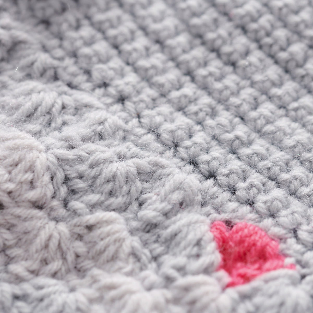 Close-up of textured gray fabric with a pink yarn ball.