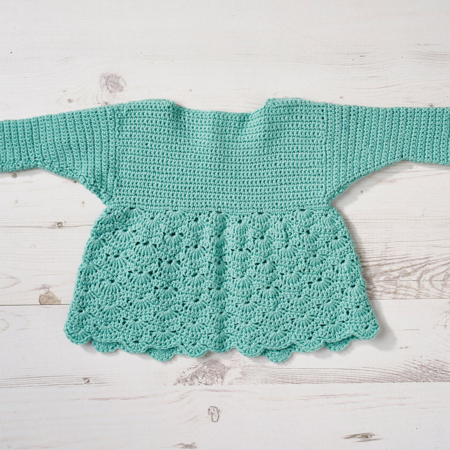 Crocheted turquoise top on a light wooden surface