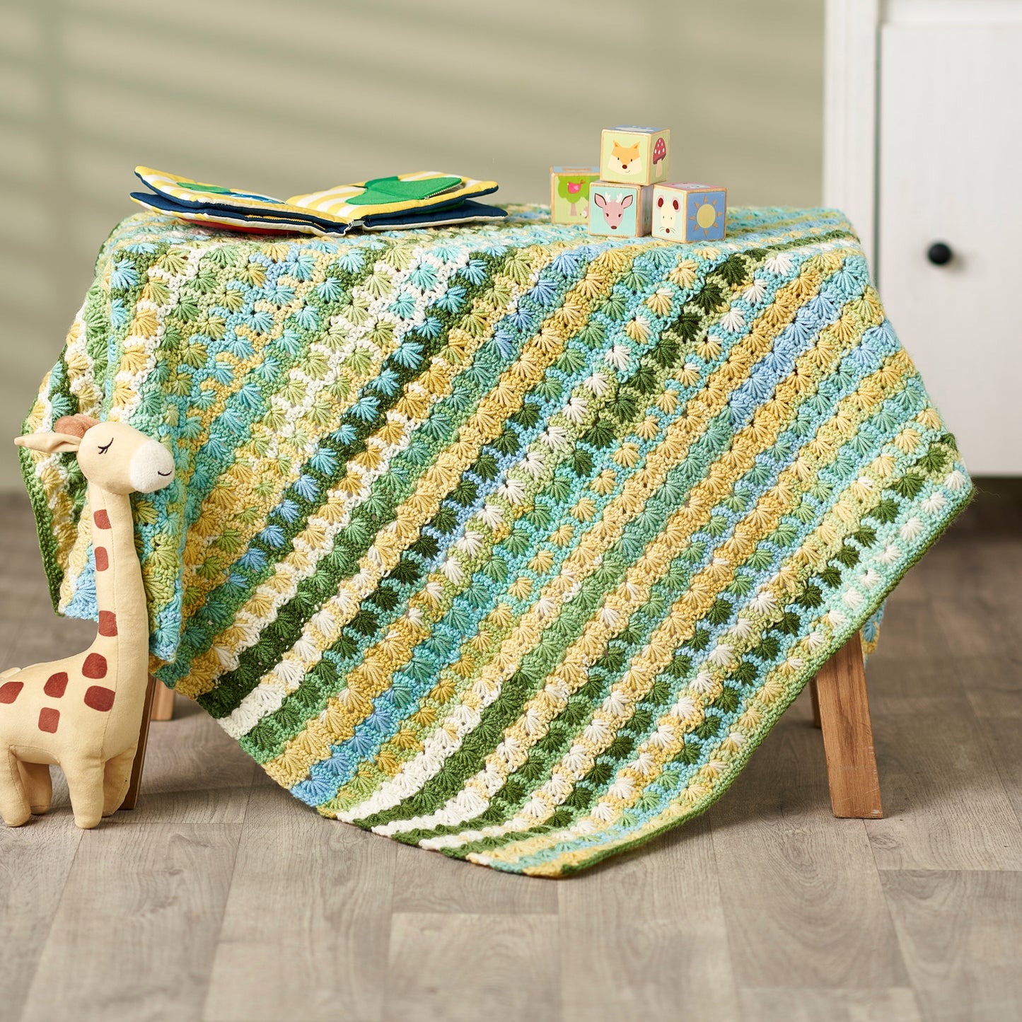 Colorful crocheted blanket on a table with toys in a room setting