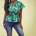 A person wearing a green peplum top with a multicolored heart pattern, paired with blue jeans.