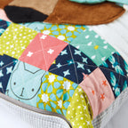 Colorful quilt with geometric patterns and a cat face design on a white background