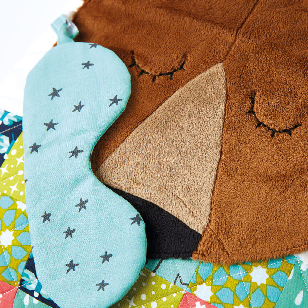 Close-up of a plush toy with a sleeping bag, featuring a fox design on a colorful background.