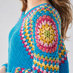 Colorful crocheted sweater with a spiral pattern on a plain background