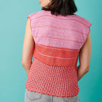Person wearing a pink and red striped crochet top against a teal background