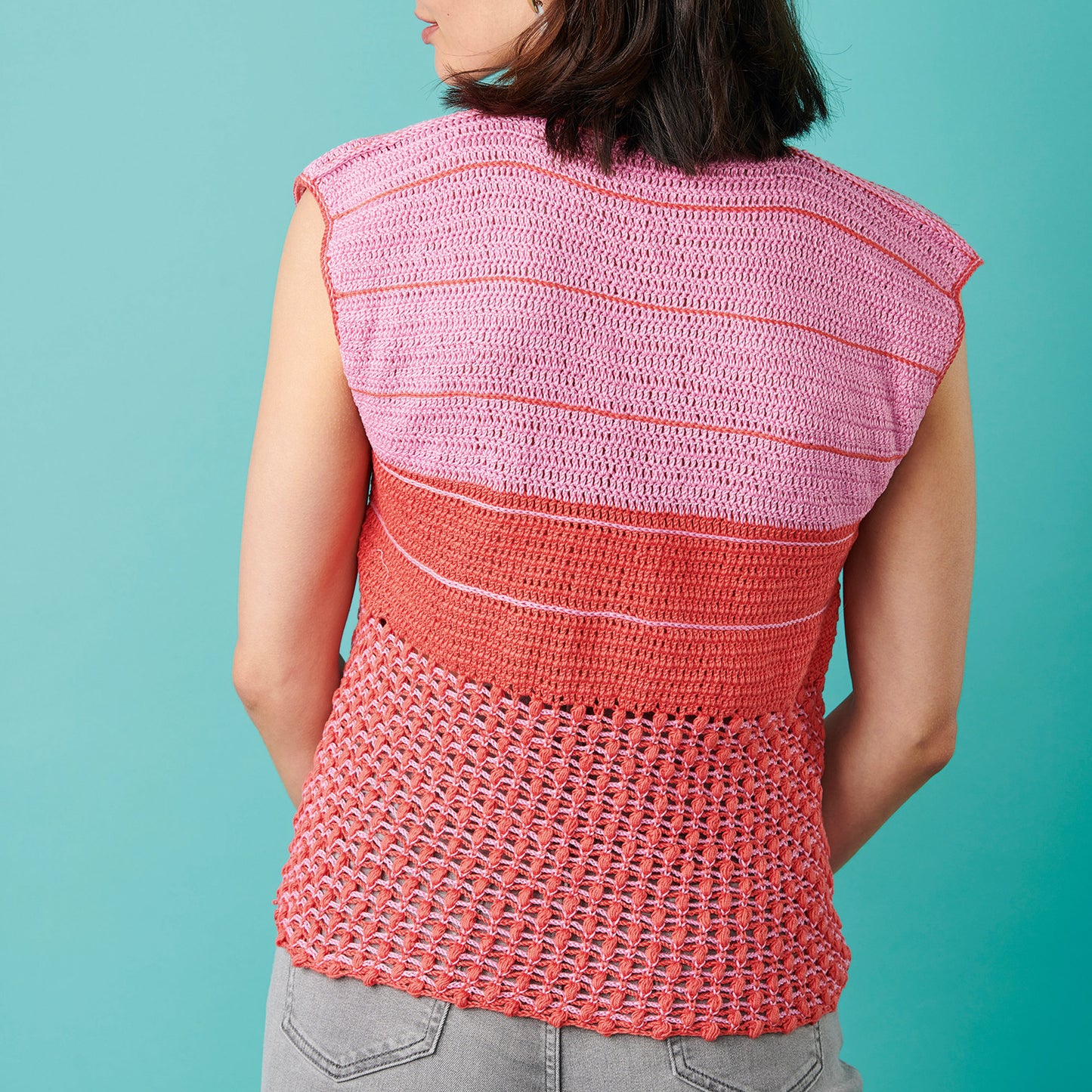 Person wearing a pink and red striped crochet top against a teal background