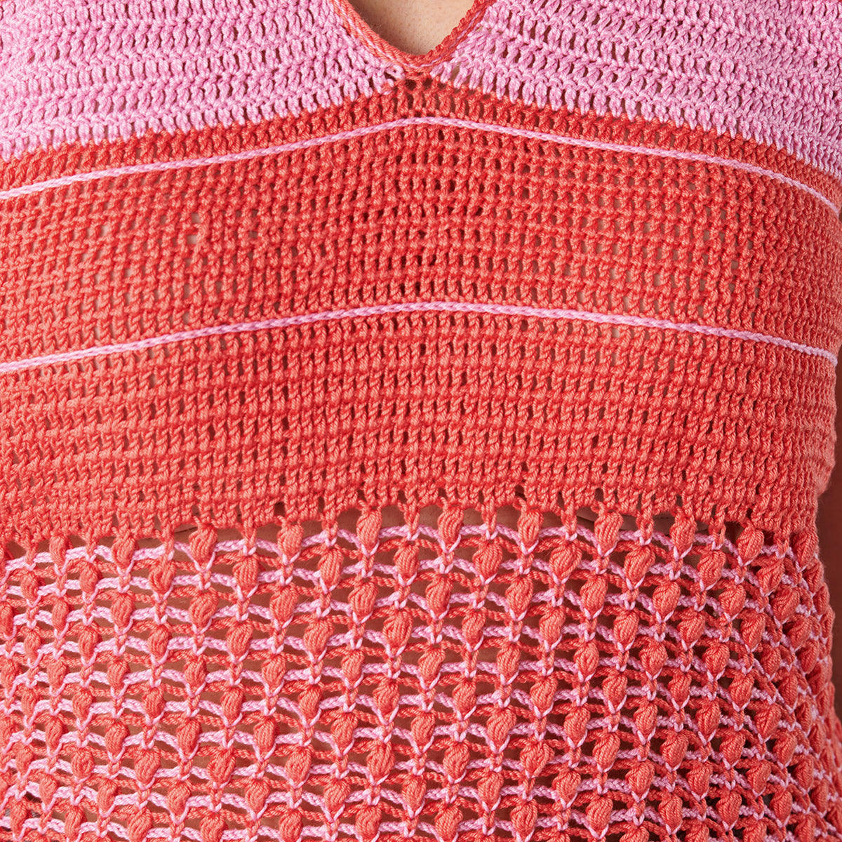 Close-up of a pink and red crocheted garment with a textured pattern.